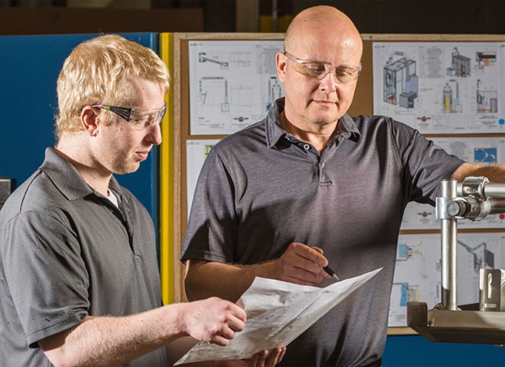 Engineers reviewing custom air knife system blueprint and component integration